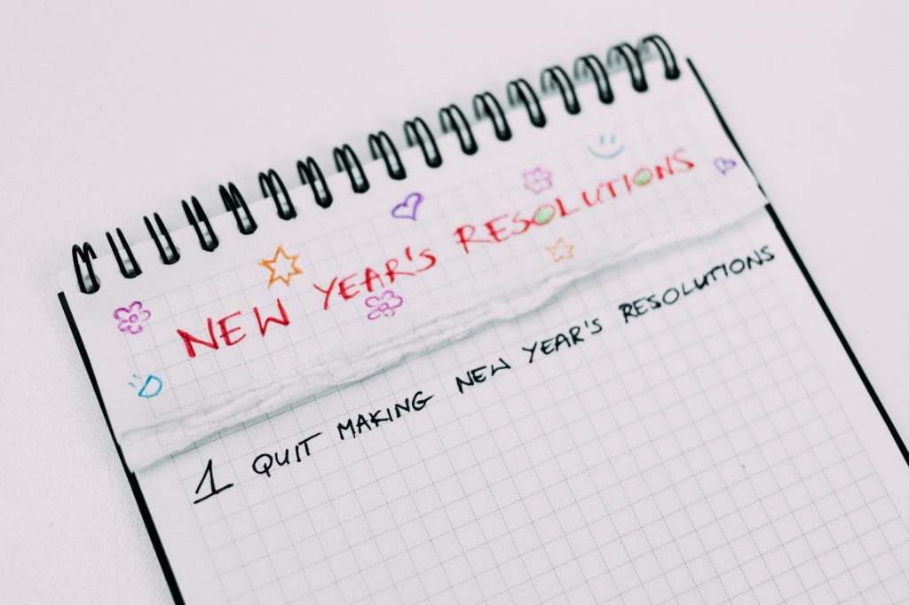 A notebook with New Year's Resolutions written on the top. #1 Quit Making New Year's Resolutions.