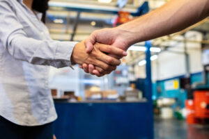 Colleagues shaking hands in factory shoo floor